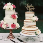 Two beautifully decorated wedding cakes with roses and buttercream frosting on glass stands